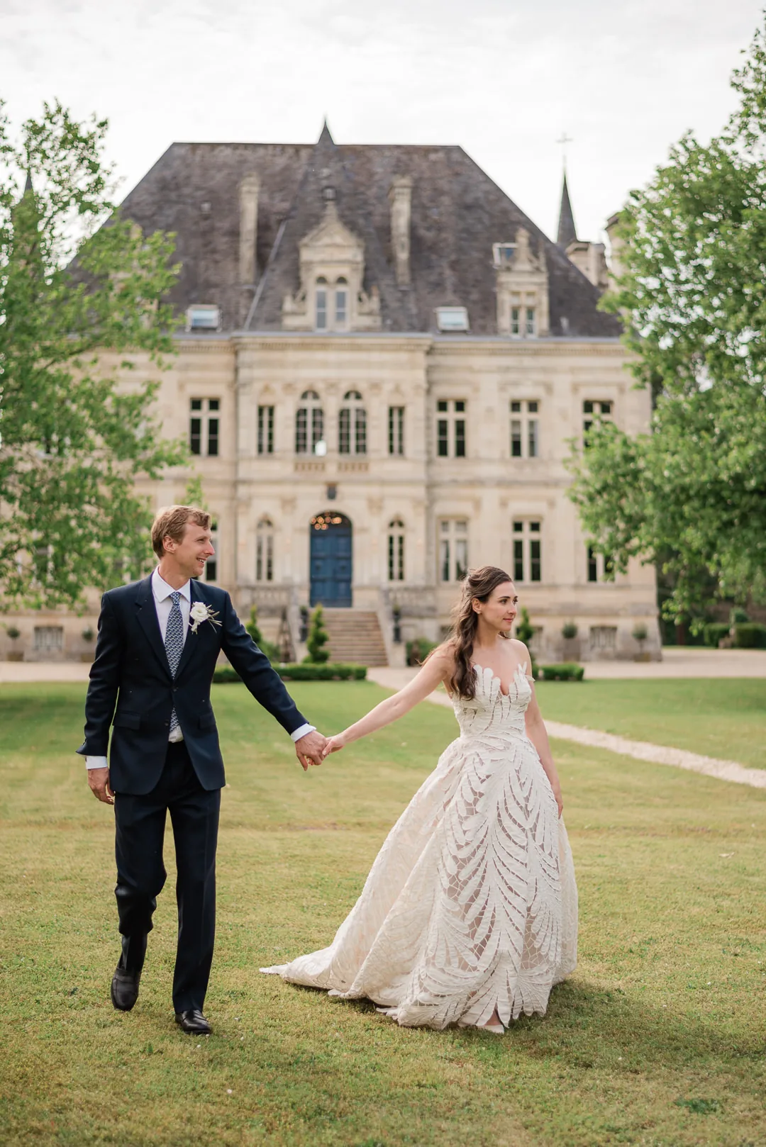 A married couple hand in hand in front of the façade